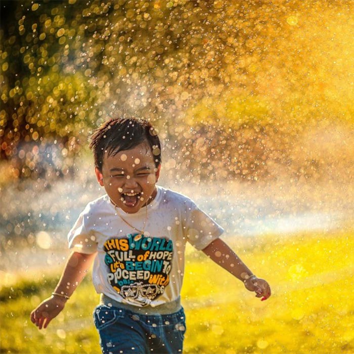 Boy running through sprinkler